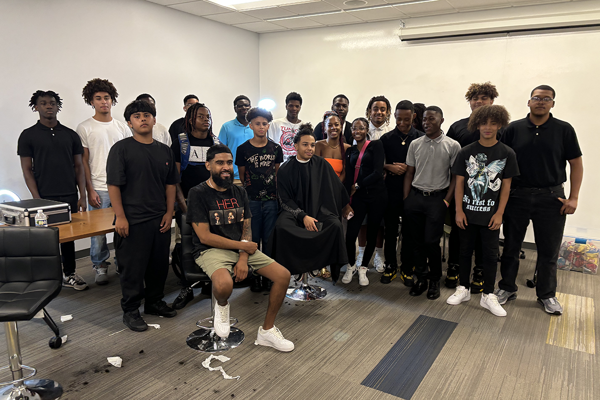 A group of students and instructors posing together in a classroom setting.