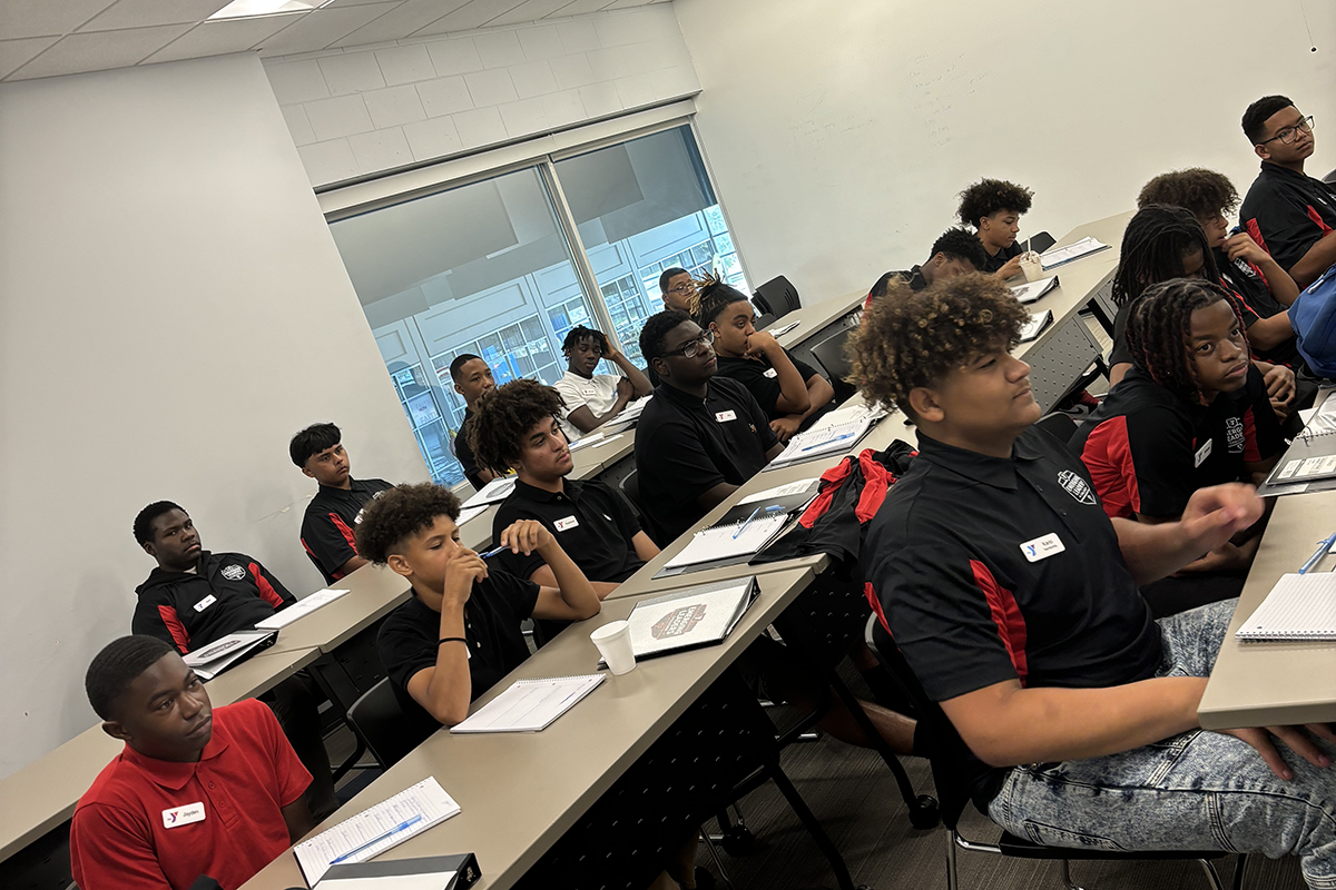 Students attentively participating in a classroom lecture, seated at desks with notebooks and materials.