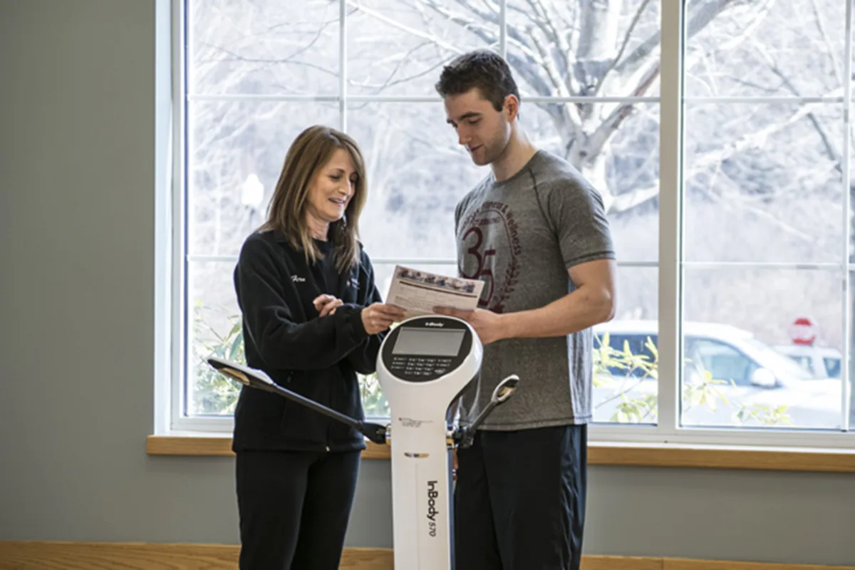 InBody with coach A fitness trainer reviewing InBody body composition results with a client near a bright window.