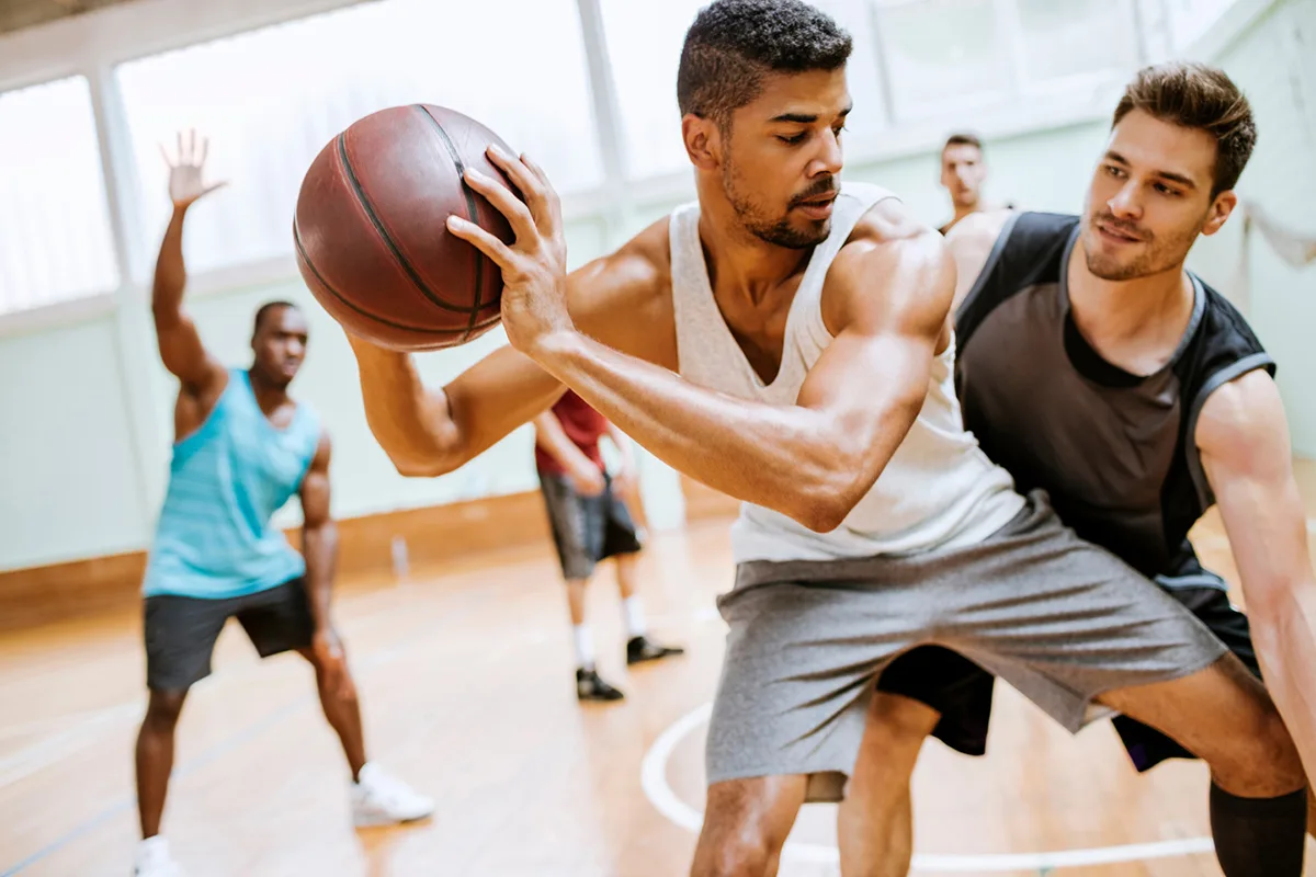 Players competing in an intense basketball game on an indoor court.