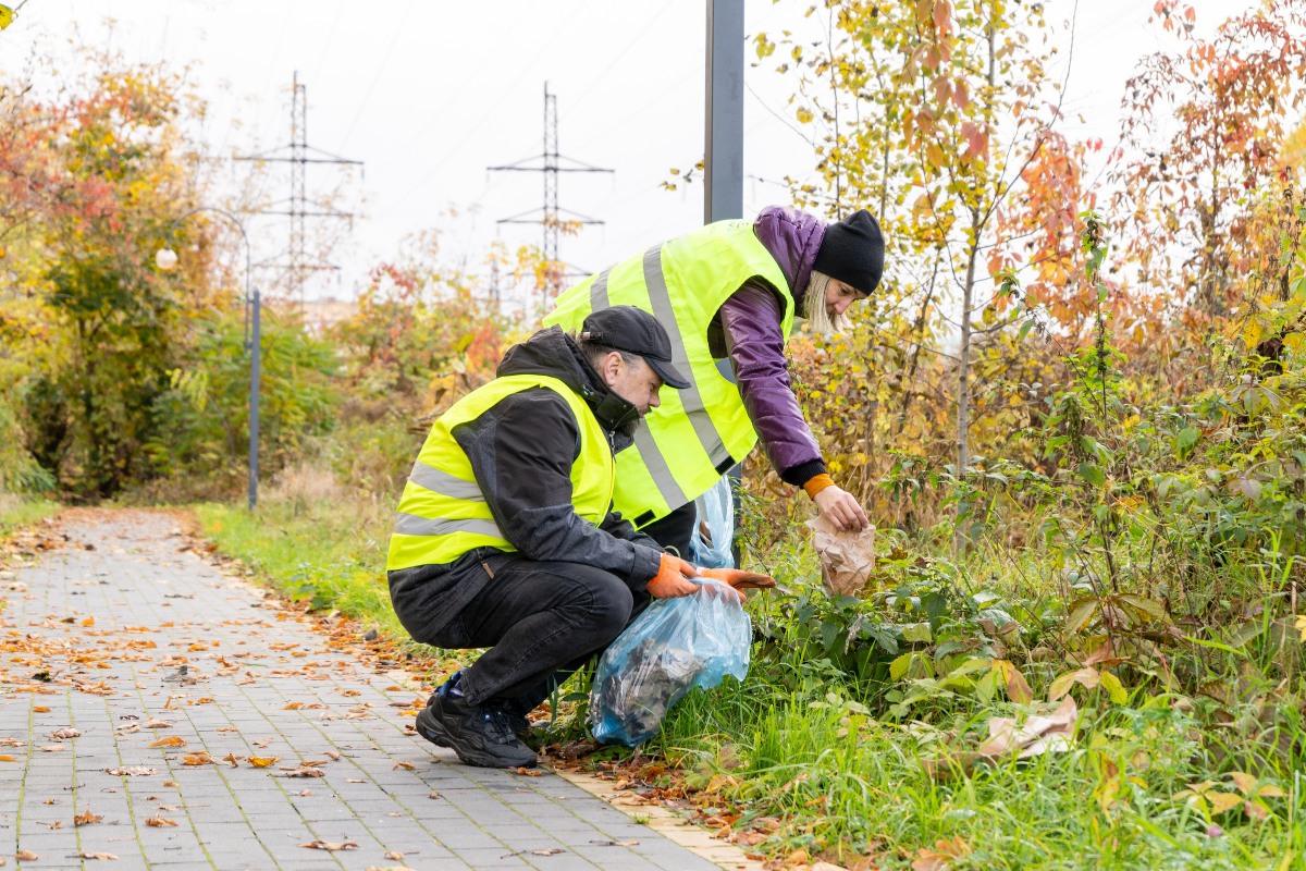 Man and woman pickup garbage on a walking path.