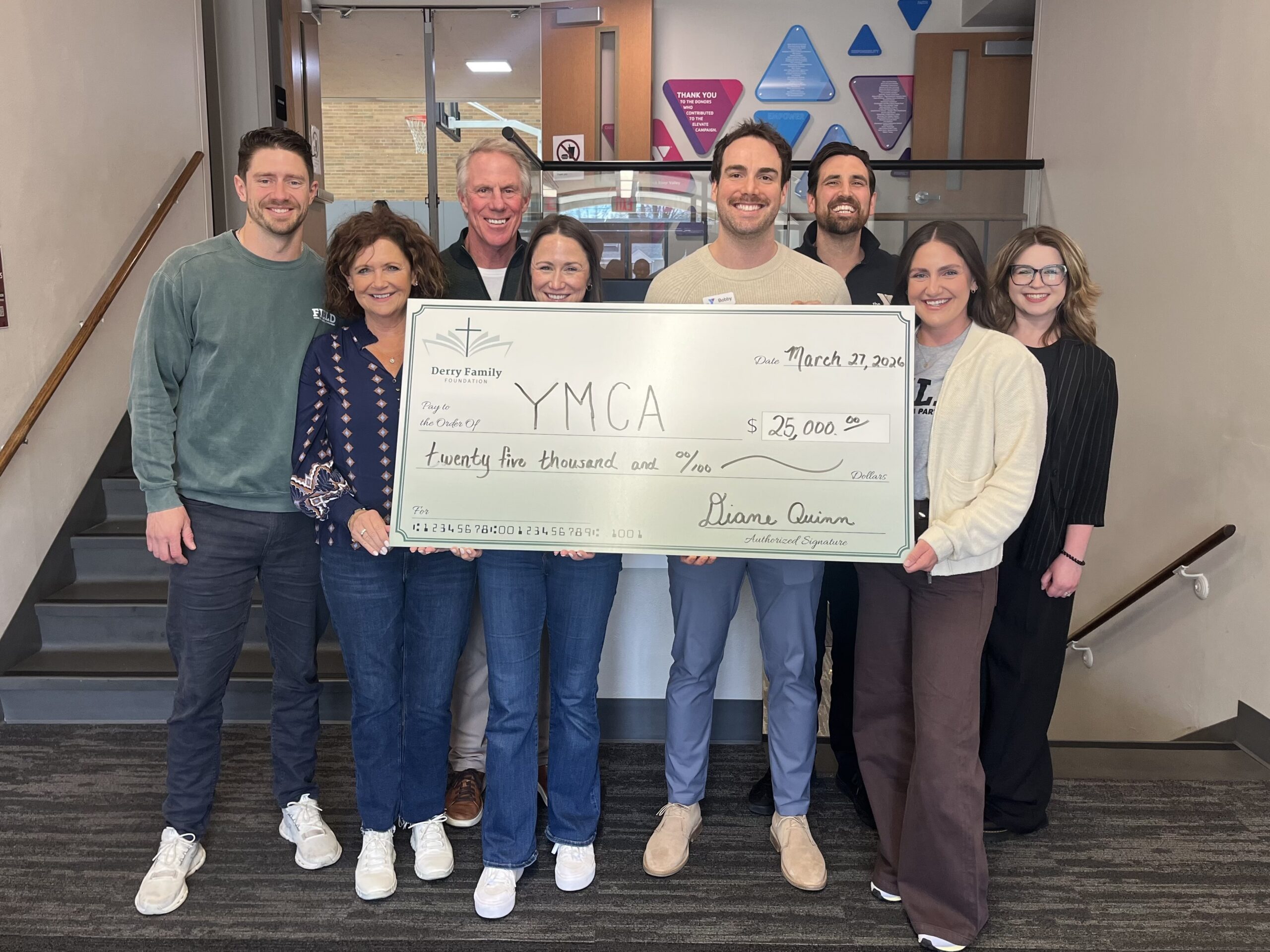 Members of the Derry Family Foundation presenting a check to YMCA staff. All holding a check and smiling at the camera
