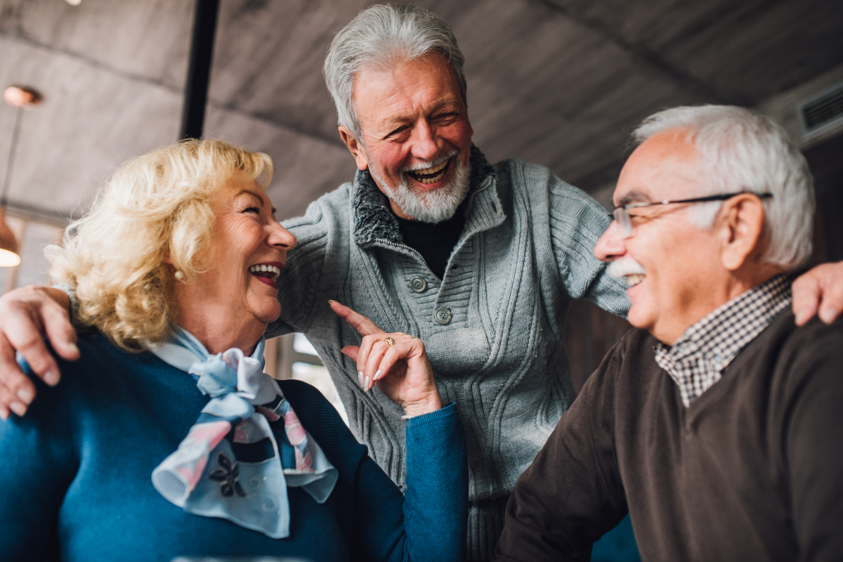 Three older adults laughing together.