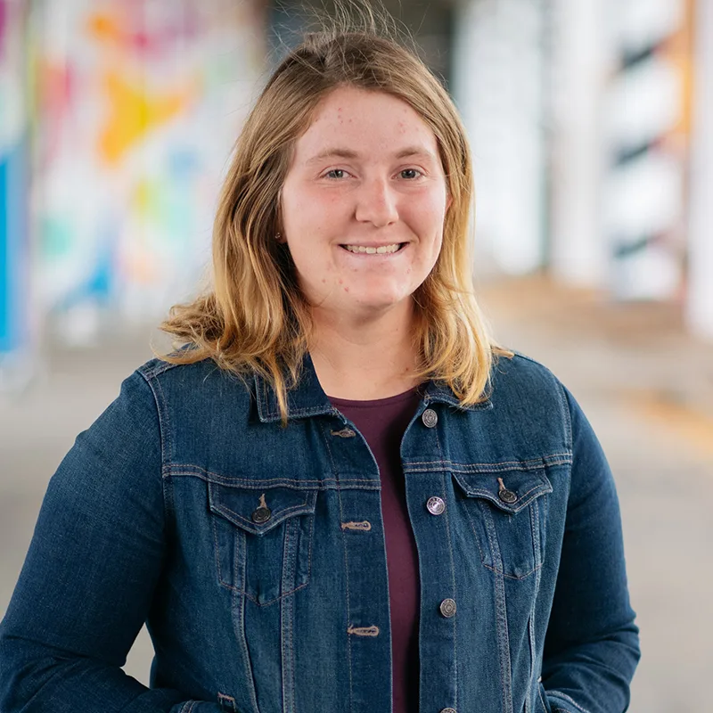 Young woman smiling, wearing denim jacket.