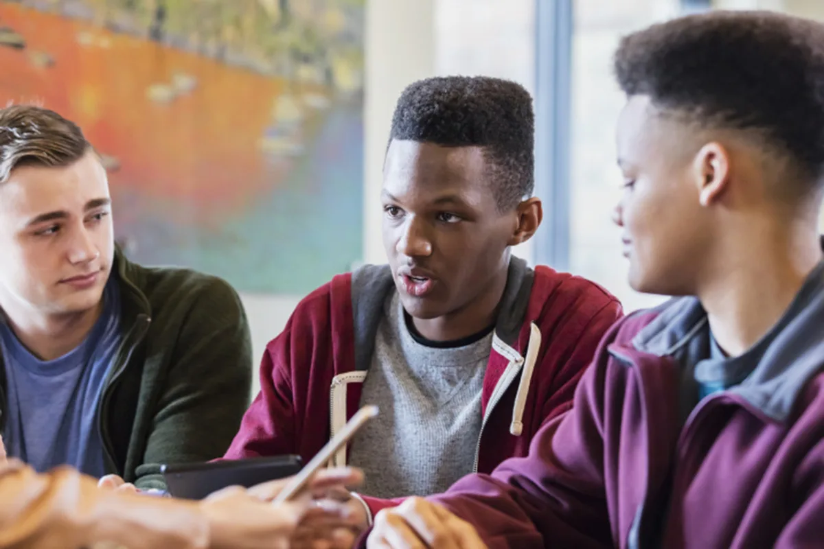 Young men having a focused discussion around a table indoors.